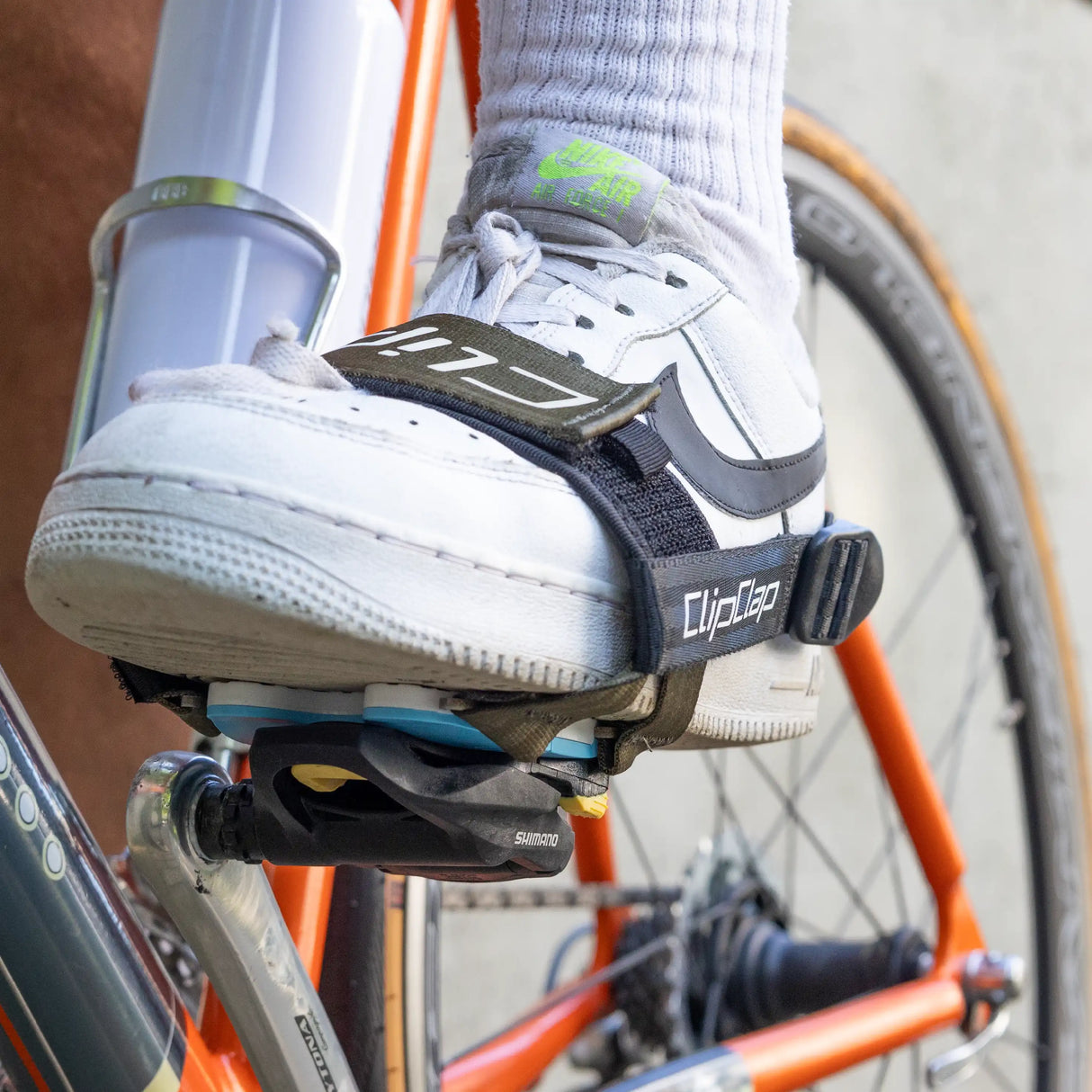 Weißer Sneaker mit Clix-Adapter in oliv und Performance Strap in Shimano Klickpedal eingeklickt, Frontansicht