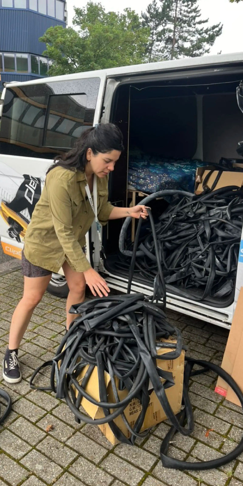 ClipClap Gründerin sichtet Transporter-Lieferung gebrauchter Fahrradschläuche und sortiert diese in Karton