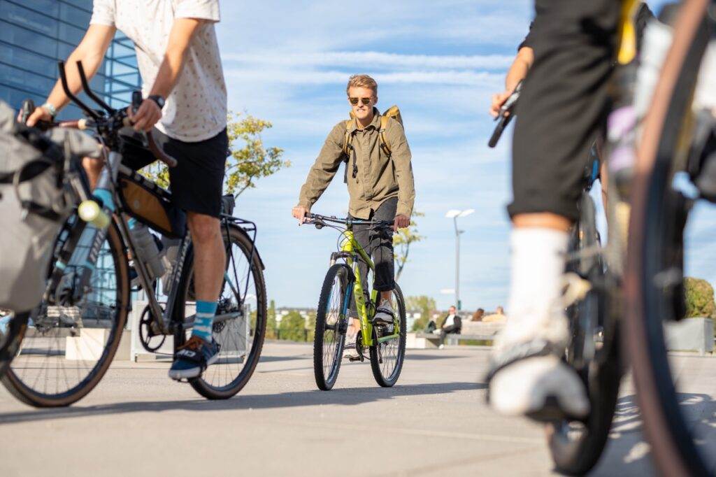 Radfahrende auf verschiedenen Fahrrädern benutzen die Klickpedal-Adapter, um aus ihren Freizeitschuhen Fahrradschuhe mit Klick zu machen